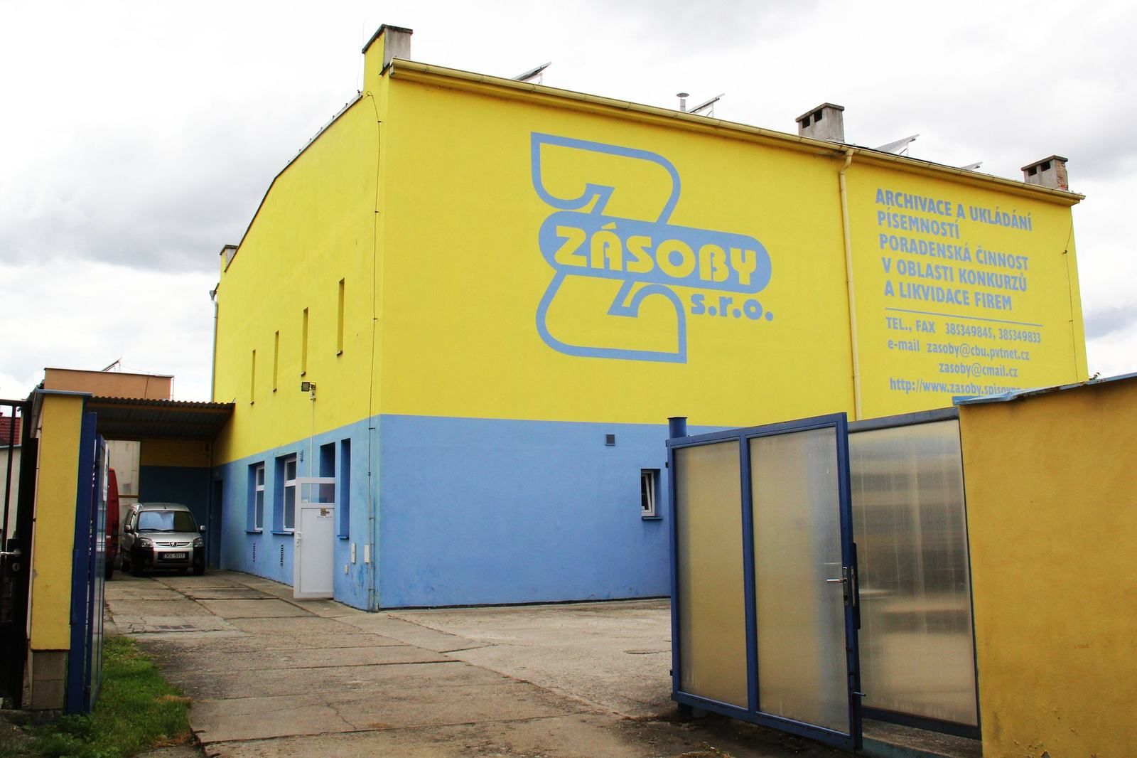 Žlutá budova spisovny ZÁSOBY s modrým soklem
